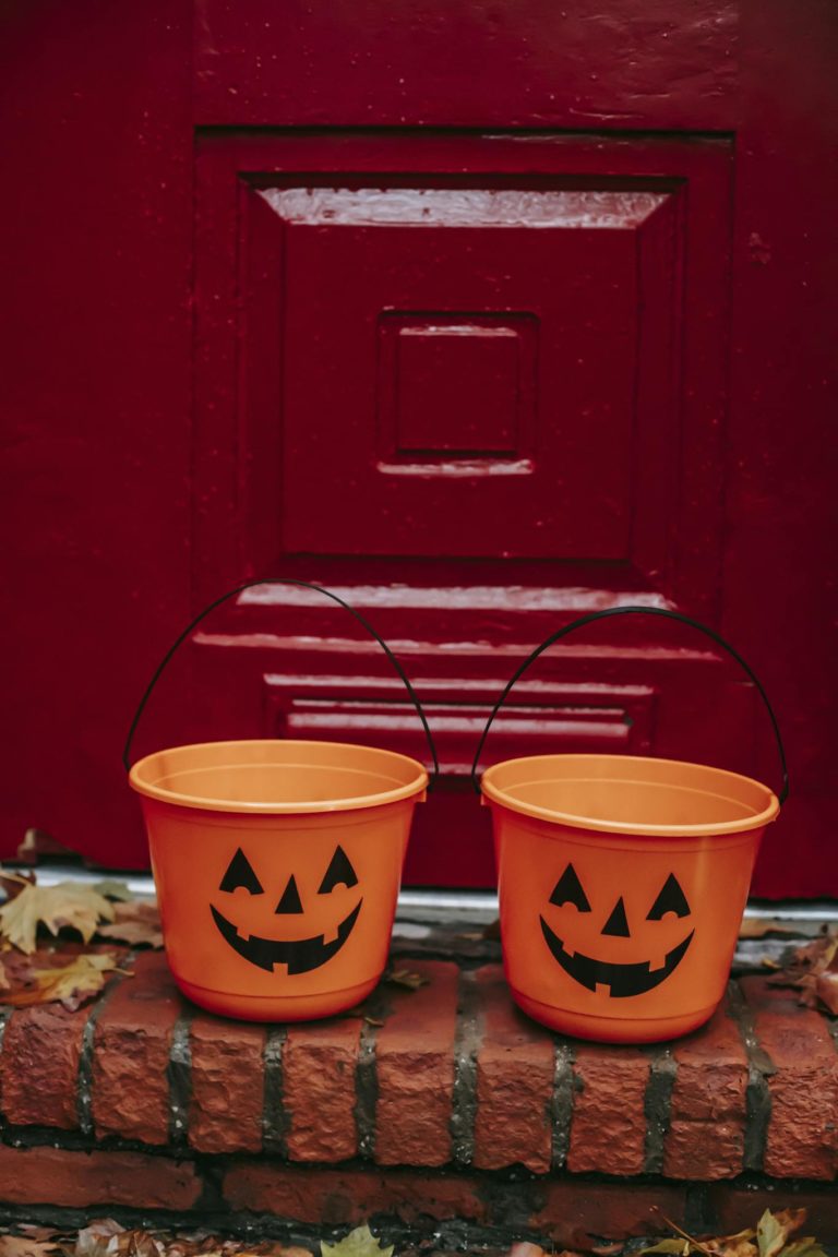 Bright orange pumpkin buckets for Trick or Treat game placed on doorway during Halloween celebration