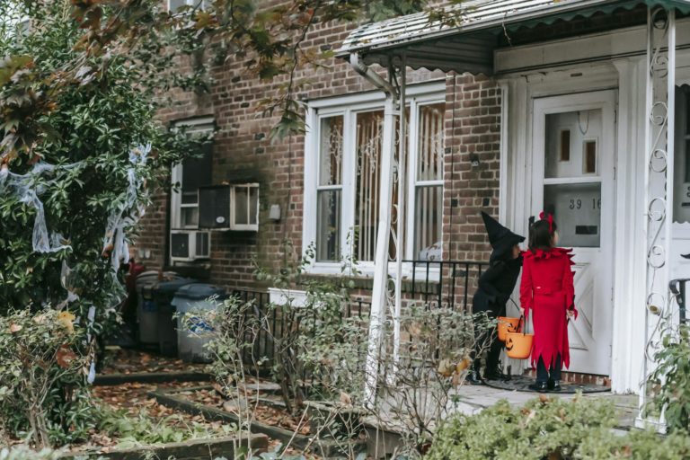 Little kids in fancy Halloween costumes outside house